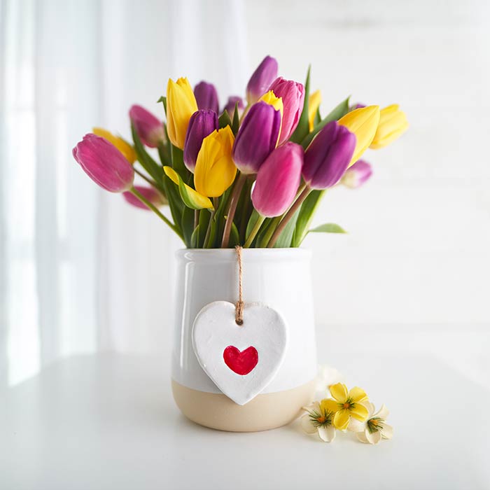 Creazione di ornamenti con impronte digitali per la Festa della Mamma. Vista frontale del lavoro artigianale con un mazzo di fiori.